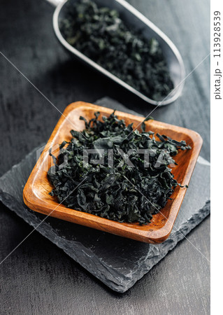 Dried wakame seaweed in bowl on black table. Dried wakame seaweed in bowl on black table. 113928539