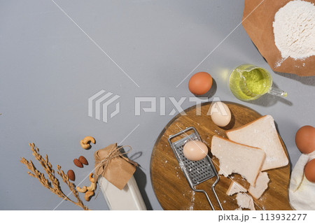 A group of baking ingredients lay flat on pastel blue kitchen table including sandwich, eggs, flour, nuts decorated with a few baking utensil. Copy space for advertising culinary product A group of baking ingredients lay flat on pastel blue kitchen table including sandwich, eggs, flour, nuts decorated with a few baking utensil. Copy space for advertising culinary product 113932277