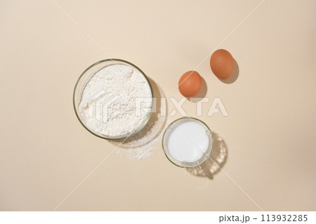 Essential baking ingredients with flour, eggs, and a cup of fresh milk flat lay presenting on the center. Ample empty space for text or adding design elements Essential baking ingredients with flour, eggs, and a cup of fresh milk flat lay presenting on the center. Ample empty space for text or adding design elements 113932285
