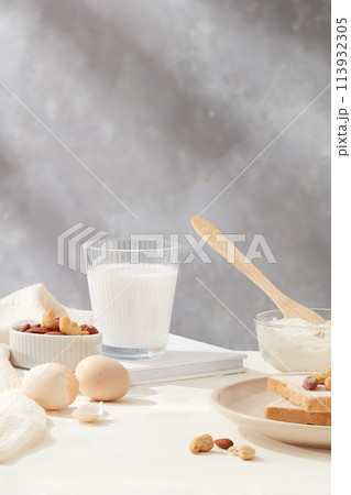 Bowl of flour, eggs and milk bottle featured on wooden chopping board against milk coffee brown background on white kitchen counter. Front view photo with copy space 113932305