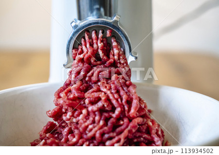 Minced meat and electric meat grinder. Cooking beef minced in the kitchen with an electric grinder Minced meat and electric meat grinder. Cooking beef minced in the kitchen with an electric grinder 113934502