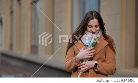 Portrait of a happy shade girl with a tulip in the background of the city in the cold season. 113934600