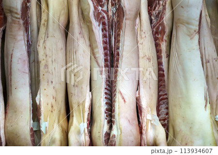 Pork meat in production. Fresh pork carcasses in a meat factory warehouse 113934607