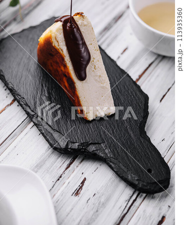 Pouring chocolate on delicious San Sebastian cheesecake 113935360