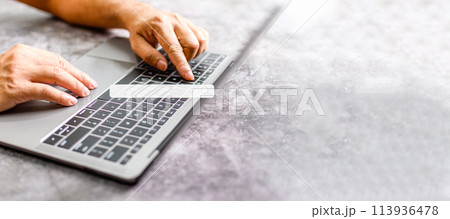 A man's hand rests on a laptop to use for job searching over the Internet. The concept for working from home, touch, website,  networking,  typing. Copy space on right for design. Blurred background 113936478
