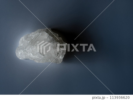 A large white rock sits on a dark blue surface A large white rock sits on a dark blue surface 113936620
