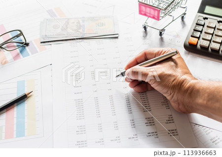 A person is writing on a piece of paper with a pen, and there is a calculator 113936663