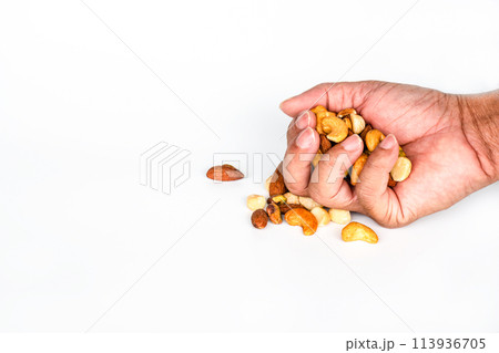 A hand is holding a handful of nuts, including almonds and cashews A hand is holding a handful of nuts, including almonds and cashews 113936705