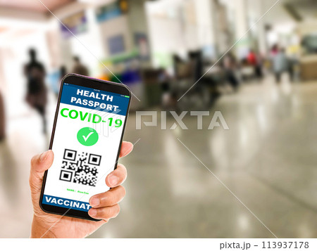 A person holding a phone with a Health Pass COVID-19 vaccine QR code on it 113937178
