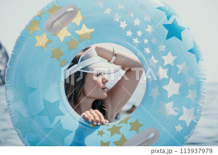 Woman summer sea. Happy woman swimming with inflatable donut on the beach in summer sunny day, surrounded by volcanic mountains. Summer vacation concept. 113937979