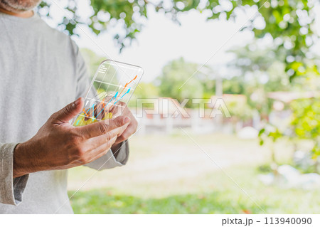 A man is holding a cell phone with a screen displaying a graph 113940090