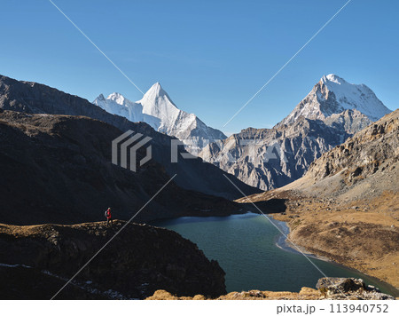 asian hiker looking at mount jampayang and chanadorje and lake boyongcuo in yading, daocheng 113940752