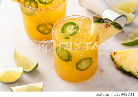 Pineapple jalapeno margarita cocktail in glasses with tajin rim 113942731