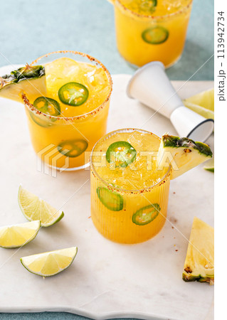 Pineapple jalapeno margarita cocktail in glasses with tajin rim 113942734