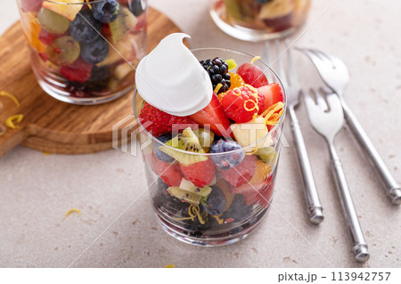 Fruit salad with berries and honey dressing served in a glass 113942757