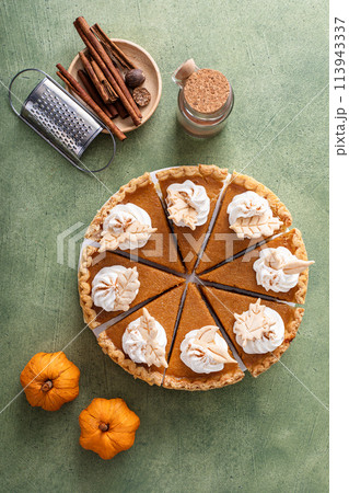 Traditional pumpkin pie topped with whipped cream cut into slices Traditional pumpkin pie topped with whipped cream cut into slices 113943337