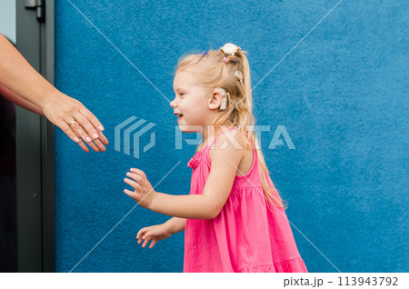 Funny baby with cochlear implant walks outdoor. Hearing aid and medicine innovating technology concept. Diversity and Inclusion and people with disability concept. Funny baby with cochlear implant walks outdoor. Hearing aid and medicine innovating technology concept. Diversity and Inclusion and people with disability concept. 113943792