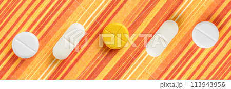 Pills and medicines arranged on an orange striped background. It's a visual representation of pharmaceuticals 113943956
