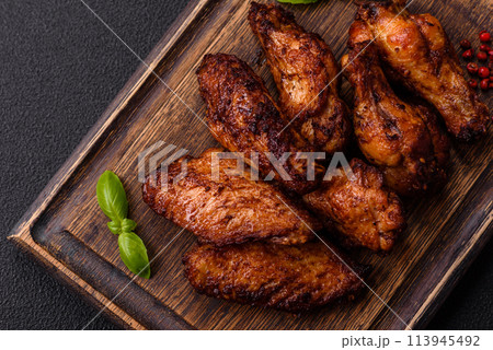 Delicious juicy chicken wings baked on the grill with salt, spices and herbs Delicious juicy chicken wings baked on the grill with salt, spices and herbs 113945492