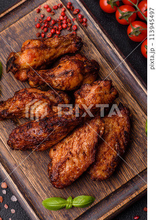 Delicious juicy chicken wings baked on the grill with salt, spices and herbs Delicious juicy chicken wings baked on the grill with salt, spices and herbs 113945497
