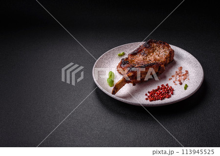 Delicious juicy beef steak on the bone, tomahawk with salt, spices and herbs Delicious juicy beef steak on the bone, tomahawk with salt, spices and herbs 113945525