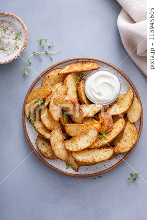 Baked potato wedges with herbs and parmesan with a dipping sauce Baked potato wedges with herbs and parmesan with a dipping sauce 113945605