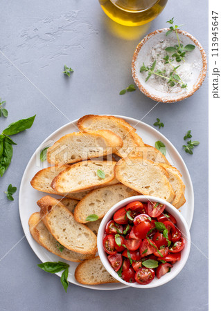 Making tomato basil bruschetta with toasted baguette and herbs 113945647