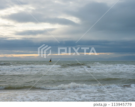 Oostende, Belgium - July 31st 2023: View from the beach towards the rough open see with a danger buoy Oostende, Belgium - July 31st 2023: View from the beach towards the rough open see with a danger buoy 113945779