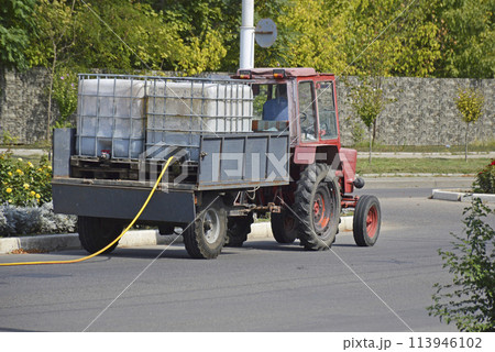 tractor with water tanks. watering flowers and plants on city streets tractor with water tanks. watering flowers and plants on city streets 113946102