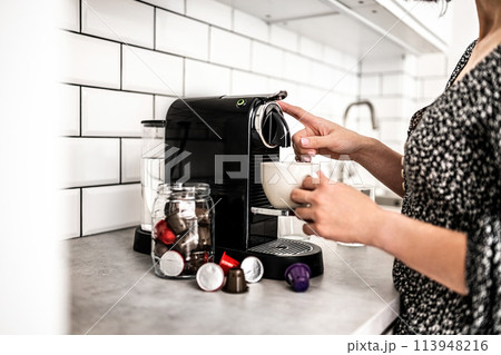 Girl with capsule coffee machine and cup at kitchen. Woman preparing italian caffeine beverage using professional espresso maker 113948216