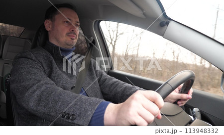 Handsome casual modern man driving car hands holding steering wheel closeup. Bearded confident pensive male driver riding automobile speed traffic transportation at autumn countryside highway Handsome casual modern man driving car hands holding steering wheel closeup. Bearded confident pensive male driver riding automobile speed traffic transportation at autumn countryside highway 113948332