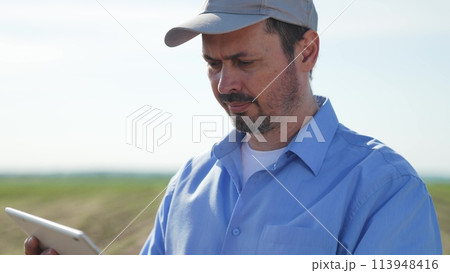 Businessman digital agricultural farmer with tablet. Face portrait of middle-aged man using gadget tablet to monitor crops track plant condition analyze growth health potential problems in field. 113948416