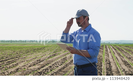 Businessman digital agricultural farmer with tablet. Professional businessman farmer male guy with serious focused look using technological digital tablet for efficient agricultural agrarian business. 113948420