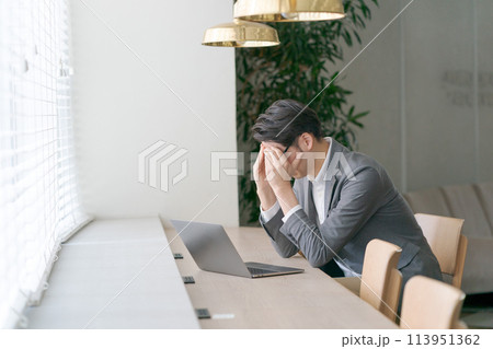 落ち込んだ表情で仕事をする男性 113951362