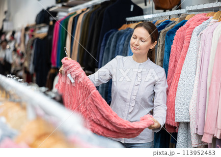 Middle-aged woman choosing convenient bathrobe in clothing store 113952483