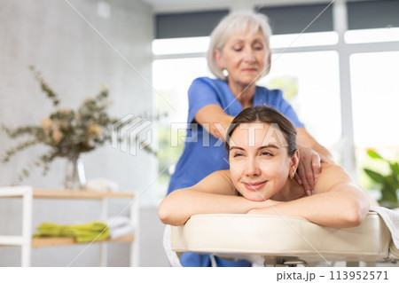 Young woman clinet satisfied with work of masseuse Young woman clinet satisfied with work of masseuse 113952571
