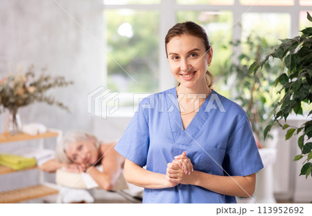 Female physiotherapist poses against background of spa salons office. Female physiotherapist poses against background of spa salons office. 113952692