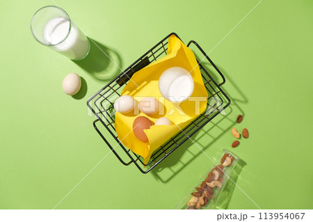 Top view of cooking concept on pastel green background. Flat lay with eggs and a cup of milk on basket. Layout for baking recipe, culinary, cooking blog 113954067