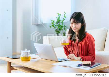 自宅リビングでのテレワークの休憩中に紅茶を飲んでリラックスをする30代の女性 113955913
