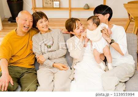 自宅のリビングで団らんするシニアの祖父母と0歳の赤ちゃんと両親の3世帯5人の大人数のファミリー 113955994