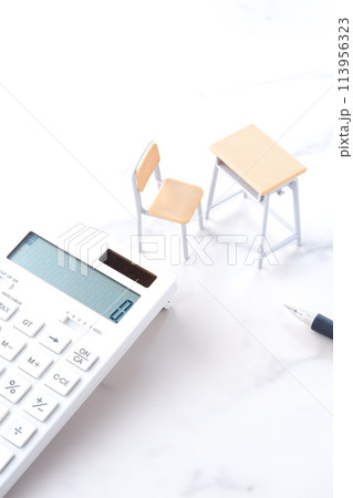 学校の机と椅子、電卓がイメージする、高騰を続けて家計を圧迫する教育費のイメージ 学校の机と椅子、電卓がイメージする、高騰を続けて家計を圧迫する教育費のイメージ 113956323