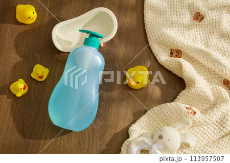 Wooden background against baby bath accessories including unlabeled bottle, baby toys, knitted bath towel, and bathtub. Mockup for baby stuffs branding, space for adding text Wooden background against baby bath accessories including unlabeled bottle, baby toys, knitted bath towel, and bathtub. Mockup for baby stuffs branding, space for adding text 113957507