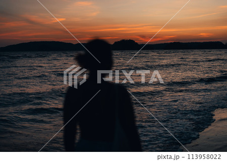 silhouette of woman at beach at dusk 113958022