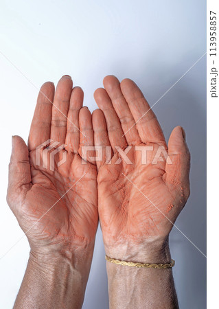 Hands of an Indian woman with red holi powder applied on hand isolated on white background. Hands of an Indian woman with red holi powder applied on hand isolated on white background. 113958857