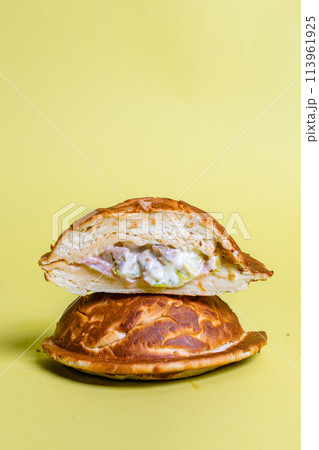 Half of burger with no top bread isolated on pastel yellow background 113961925