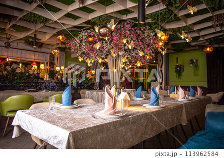 Elegant restaurant interior with decorated ceiling and table settings Elegant restaurant interior with decorated ceiling and table settings 113962584