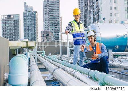 engineer teamwork technician workers service hotel boiler tank hot water supply pipe system. team working safety checking maintenance pipeline heating water delivery line at roof top outdoor. 113967015