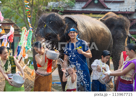 Songkran festival. Northern Thai people in Traditional clothes dressing splashing water together in Songkran day cultural festival with elephant background. Songkran festival. Northern Thai people in Traditional clothes dressing splashing water together in Songkran day cultural festival with elephant background. 113967715