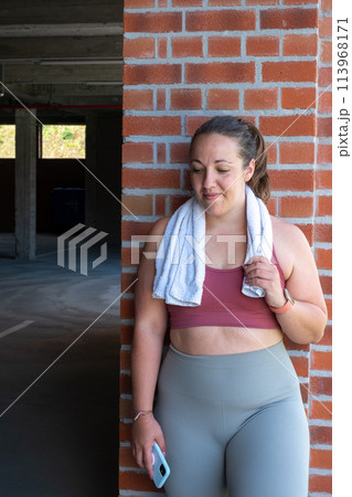 Everyday Athlete: Curvy Woman Enjoying Post-Workout Break by Brick Pillar 113968171