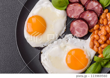 English breakfast with fried eggs, bacon, beans, tomatoes, spices and herbs English breakfast with fried eggs, bacon, beans, tomatoes, spices and herbs 113969560